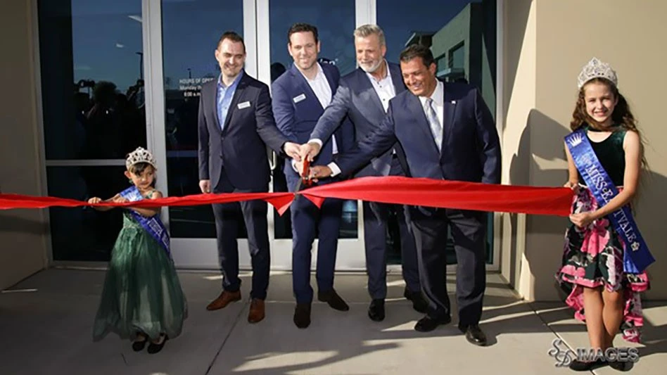 a photo of four men cutting a red ribbon held by two girls wearing crowns