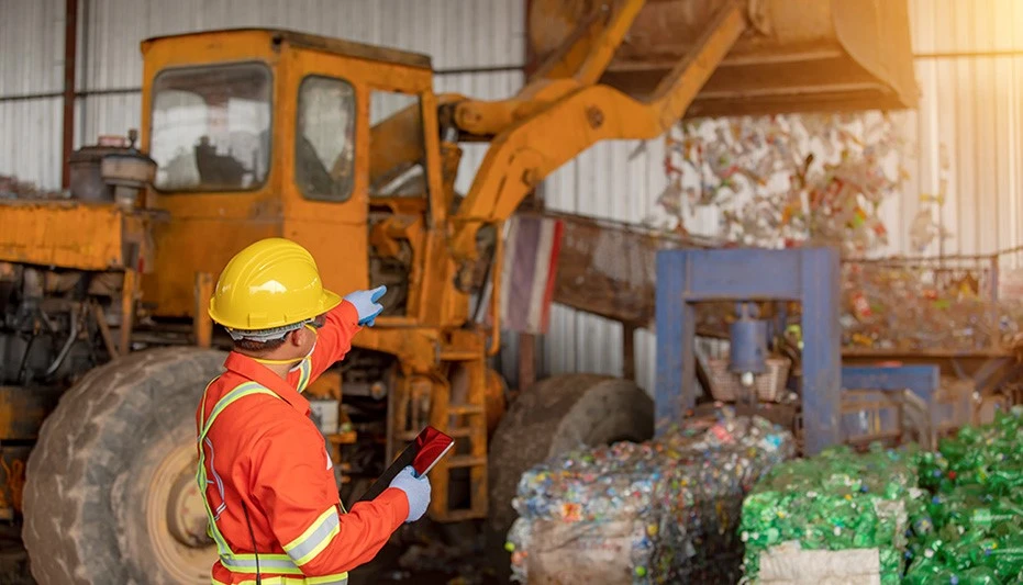 Worker in safety gear overseeing work inside a material recovery facility
