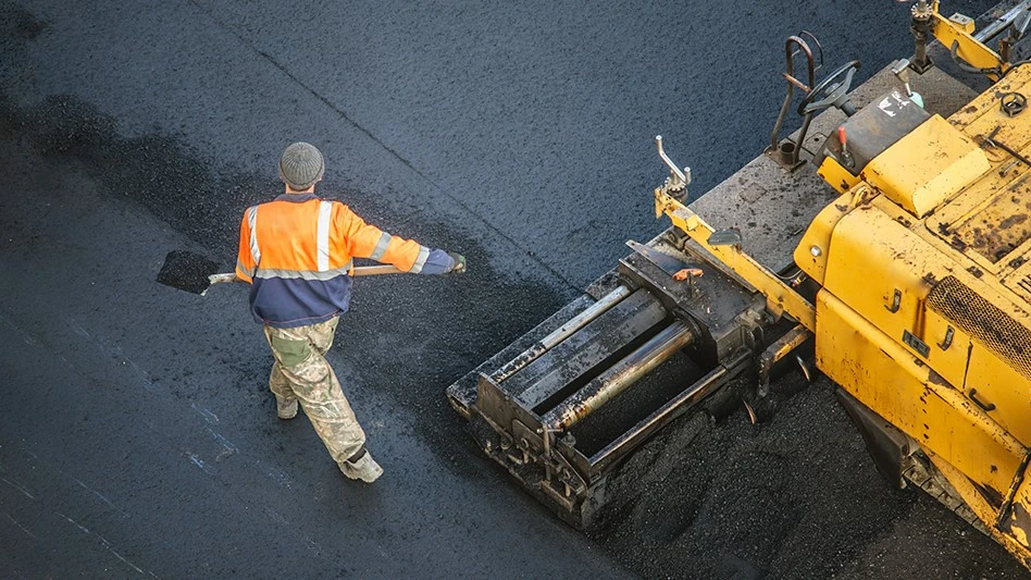 Worker lays asphalt pavement