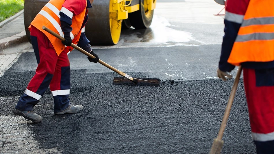workers lay asphalt pavement