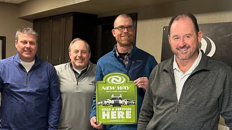 four men gather around a plaque