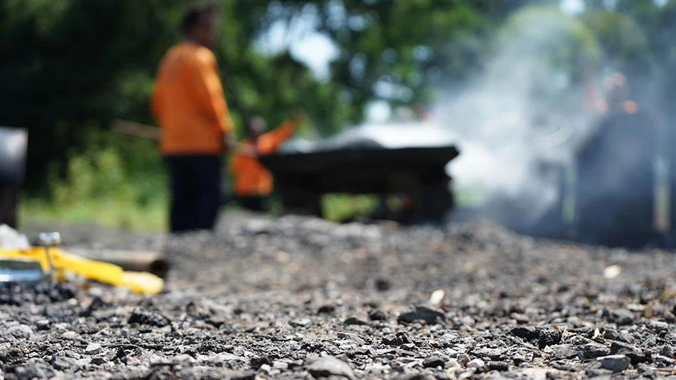 hot asphalt on road with construction workers in background