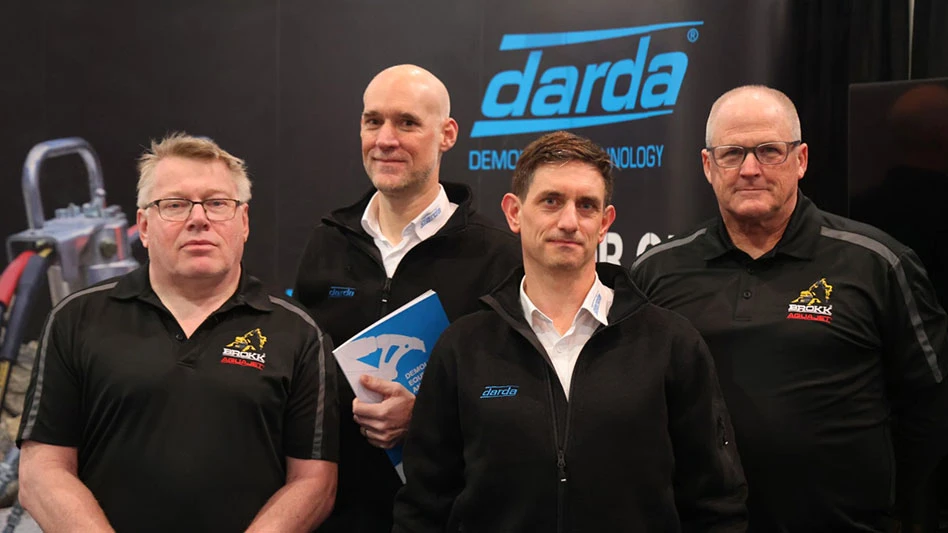 photo of four white men in black shirts standing in front of a Darda-branded exhibition booth
