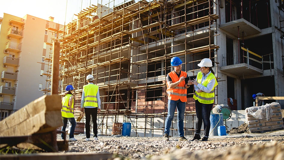 group of construction workers in hi-vis vests and hard hats discussing at jobsite