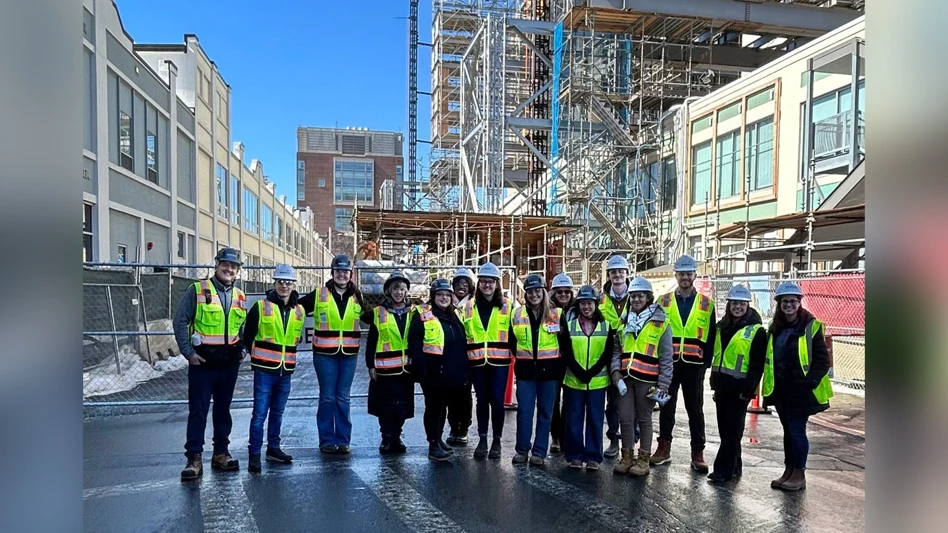 group of people in hi-vis vests, hardhats in front of scaffolding