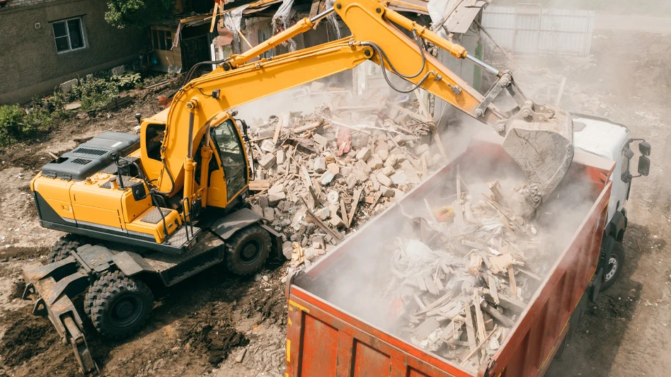 excavator putting construction and demolition waste materials in dumpster